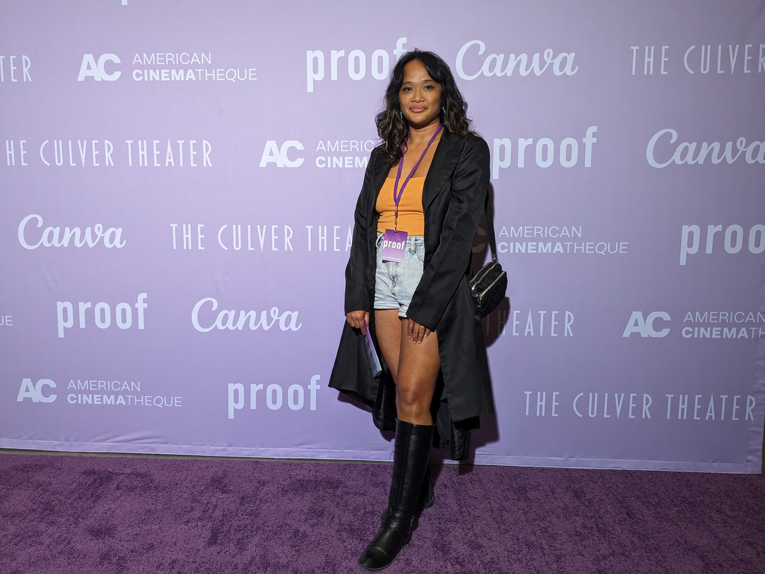 Mailyne on the step and repeat in front of the purple backdrop showing logos of proof, canva, Culver theater and American Cinematheque